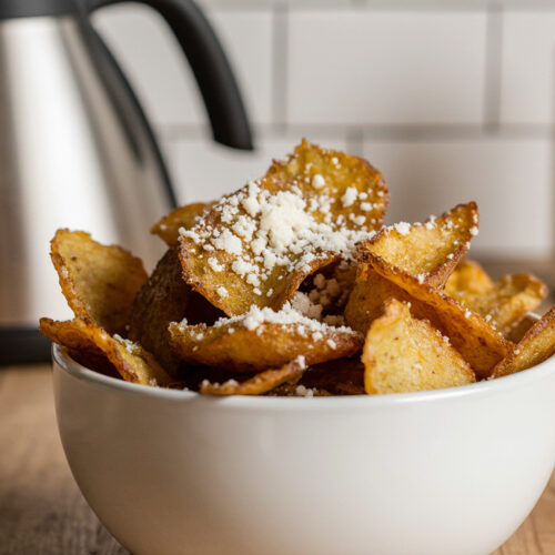 Bowl of homemade parmesan truffle chips on a kitchen table