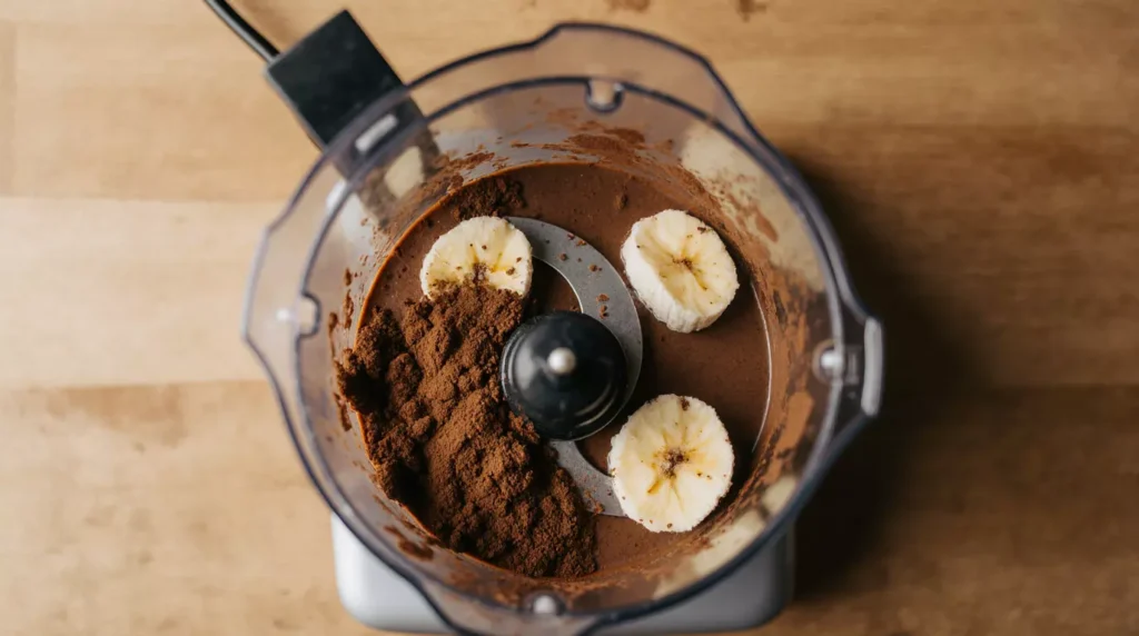 Frozen bananas and cocoa being blended for chocolate nice cream banana