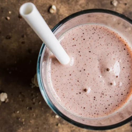 Close up view of a creamy strawberry smoothie with smooth texture and light pink color.