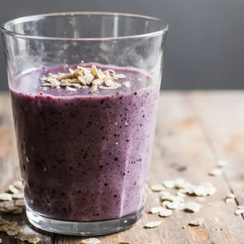 A taro root smoothie beside meal prep bowls with oats and fruit on a kitchen table.