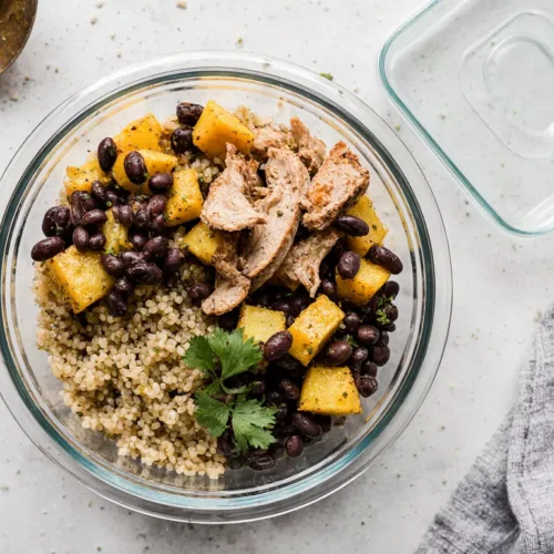 Easy microwave meal prep bowl with quinoa, beans, vegetables, and chicken in a glass container