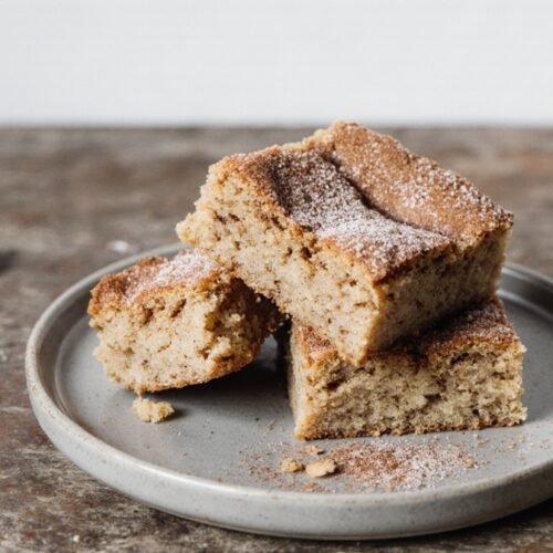 Stack of vegan snickerdoodle blondies with cinnamon sugar topping on a plain plate