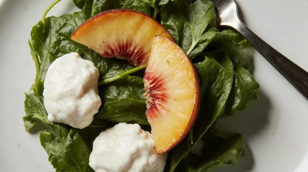 Close-up of arugula leaves peach slices and burrata cheese in a salad